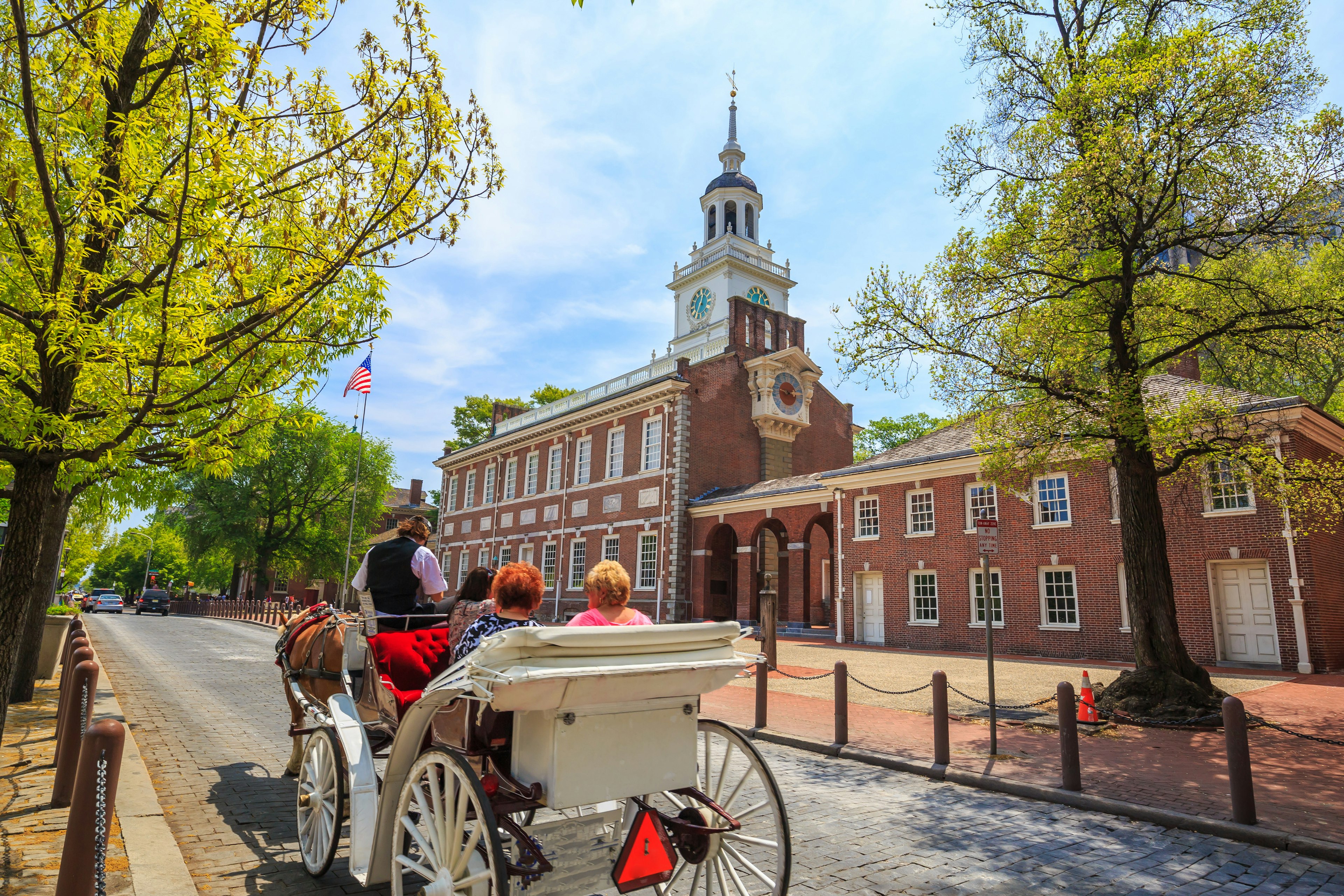 A horse-drawn carriage passes Independence Hall in Philadelphia, Pennsylvania, USA