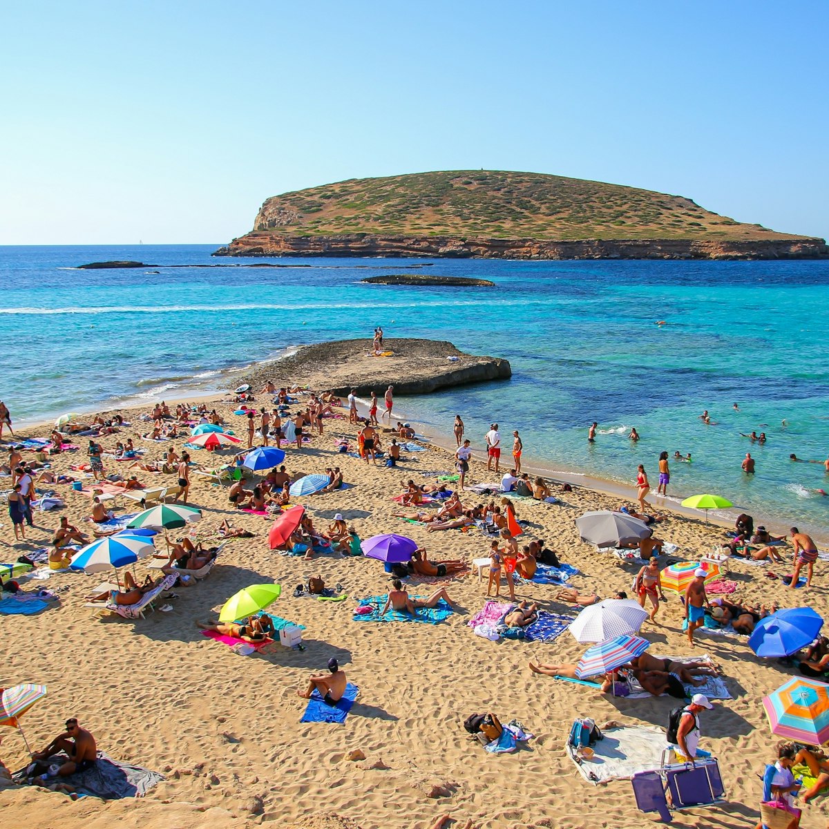 Tourists sunbathing by the Mediterranean Sea on the Platges de Comte on the northwestern coast of Ibiza.
