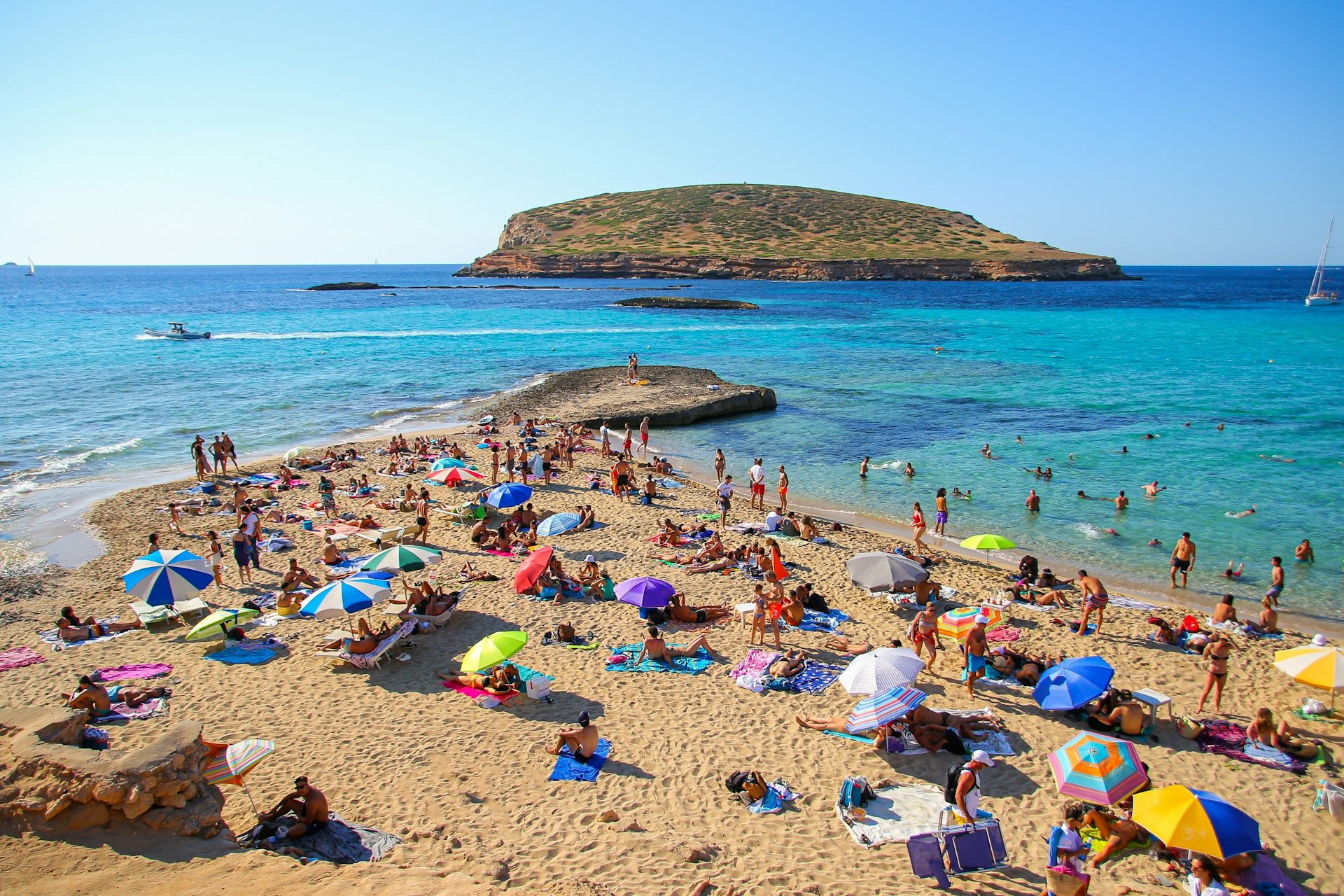 Tourists sunbathing by the Mediterranean Sea on the Platges de Comte on the northwestern coast of Ibiza