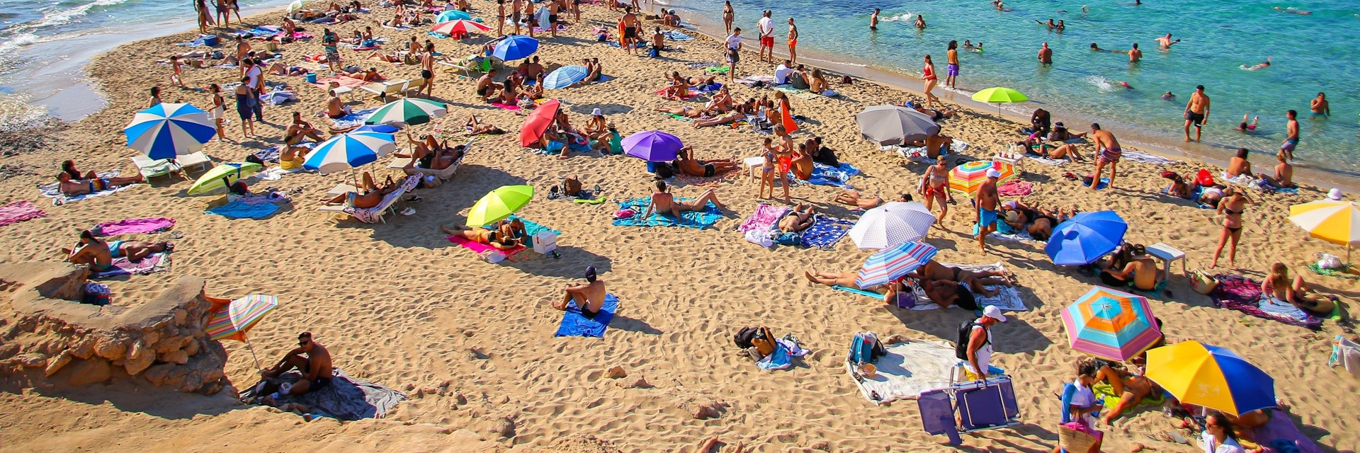 Tourists sunbathing by the Mediterranean Sea on the Platges de Comte on the northwestern coast of Ibiza.