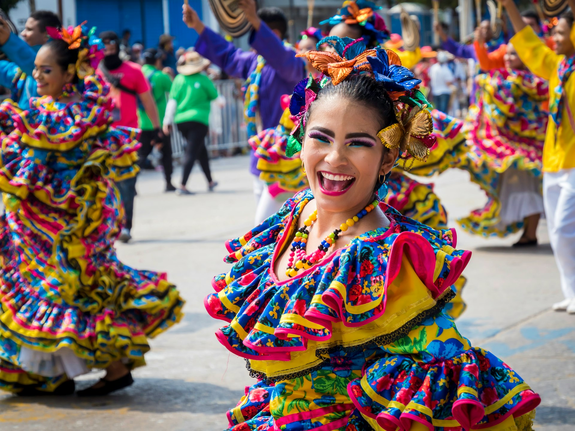 Dancers in colorful dress move along a street parade