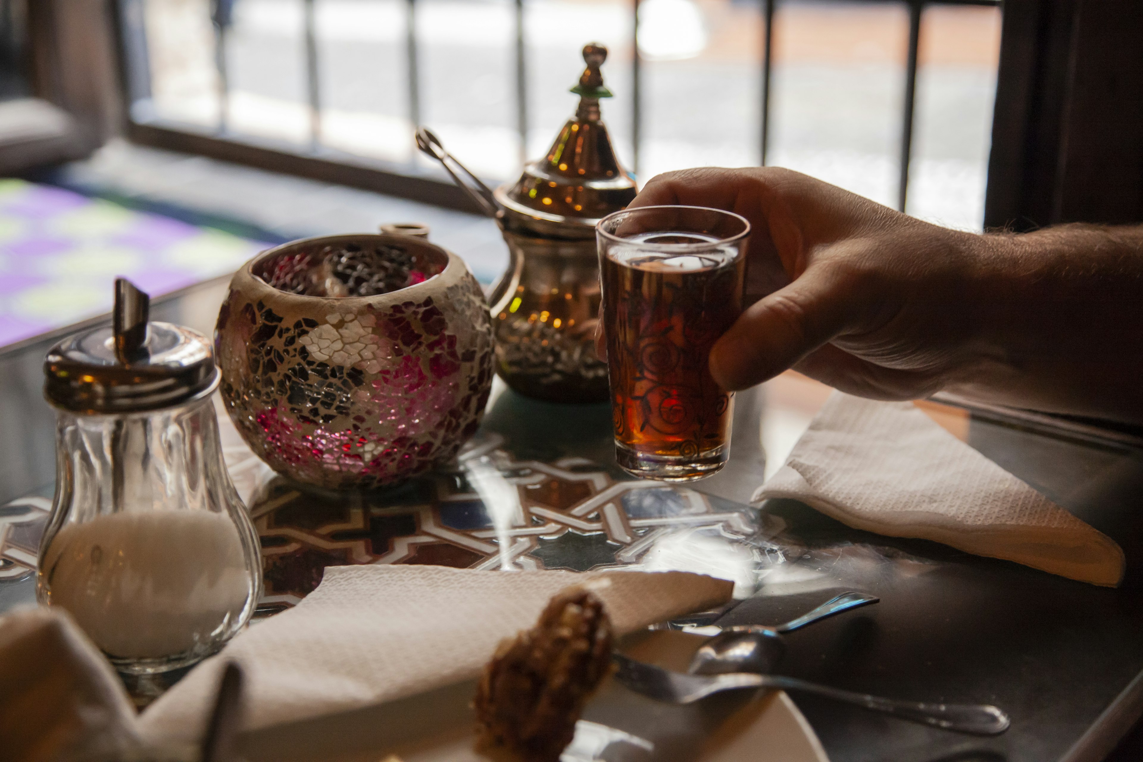 A hand holds a glass of tea in a small tea shop