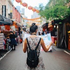 A young woman solo traveler checking a map in a Singapore street market