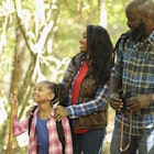 A mum, dad and daughter hiking through a forested area in Texas