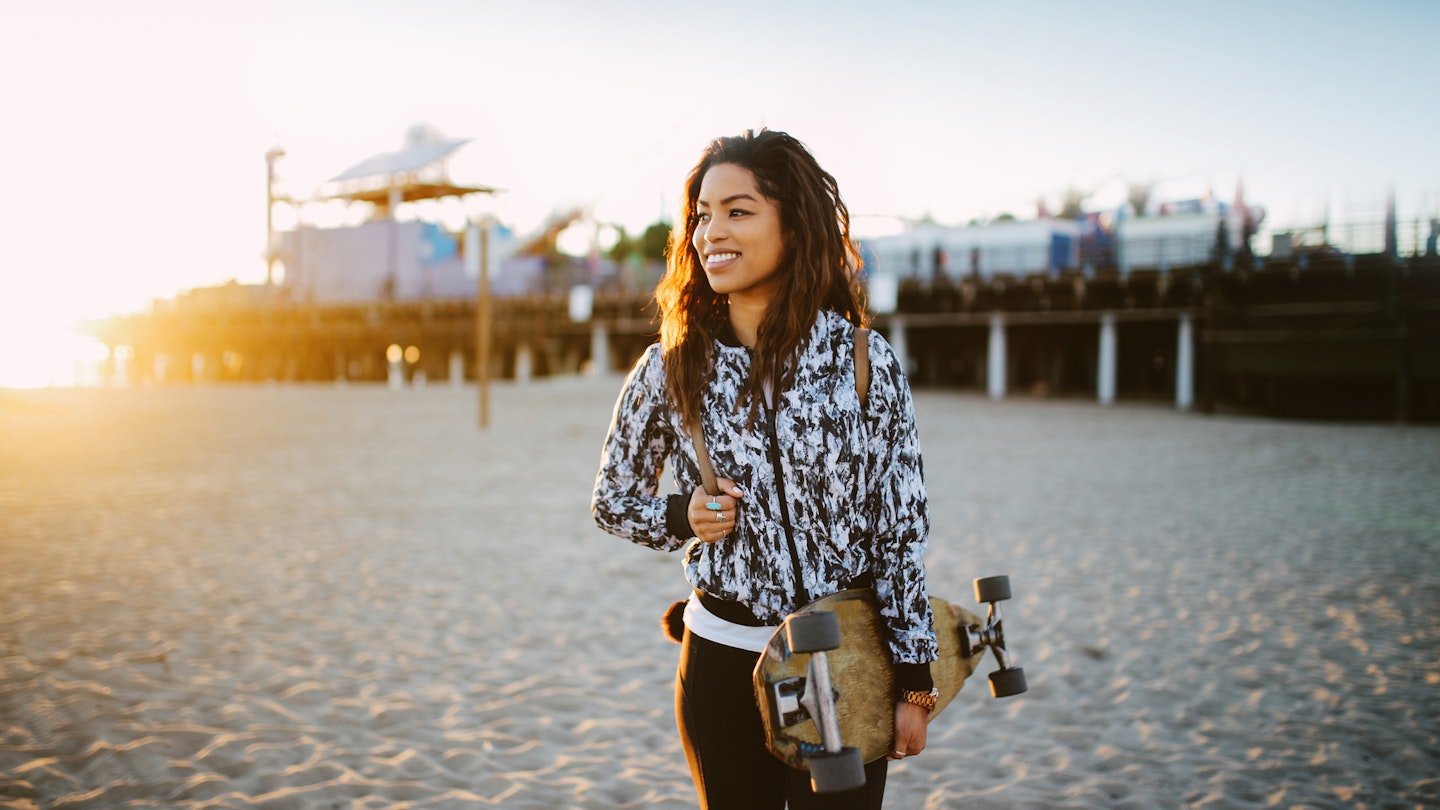 Young mixed Latina woman enjoying the beautiful Santa Monica beach in Los Angeles, California. She is wearing a fashionable spring jacket, going to meet her friends near the beach, holding an old school longboard under her arm.
1133479582
relaxation, only women, one person, beautiful woman, enjoyment, satisfaction, long hair, beauty, 25-29 years, women, horizontal, summer, curly hair, jacket, portrait, city life, fashion, side view, california, lifestyles, outdoors, young women, beautiful people, santa monica, latin american and hispanic ethnicity, venice beach, happiness, fashionable, city of los angeles, latin american culture, cool attitude, walking, mixed race person, los angeles county, real people, candid, street style, retro style, skateboard, tan, surfing, skateboarding, longboard skating, hipster - person, sunset, back lit, beach, pier, toothy smile