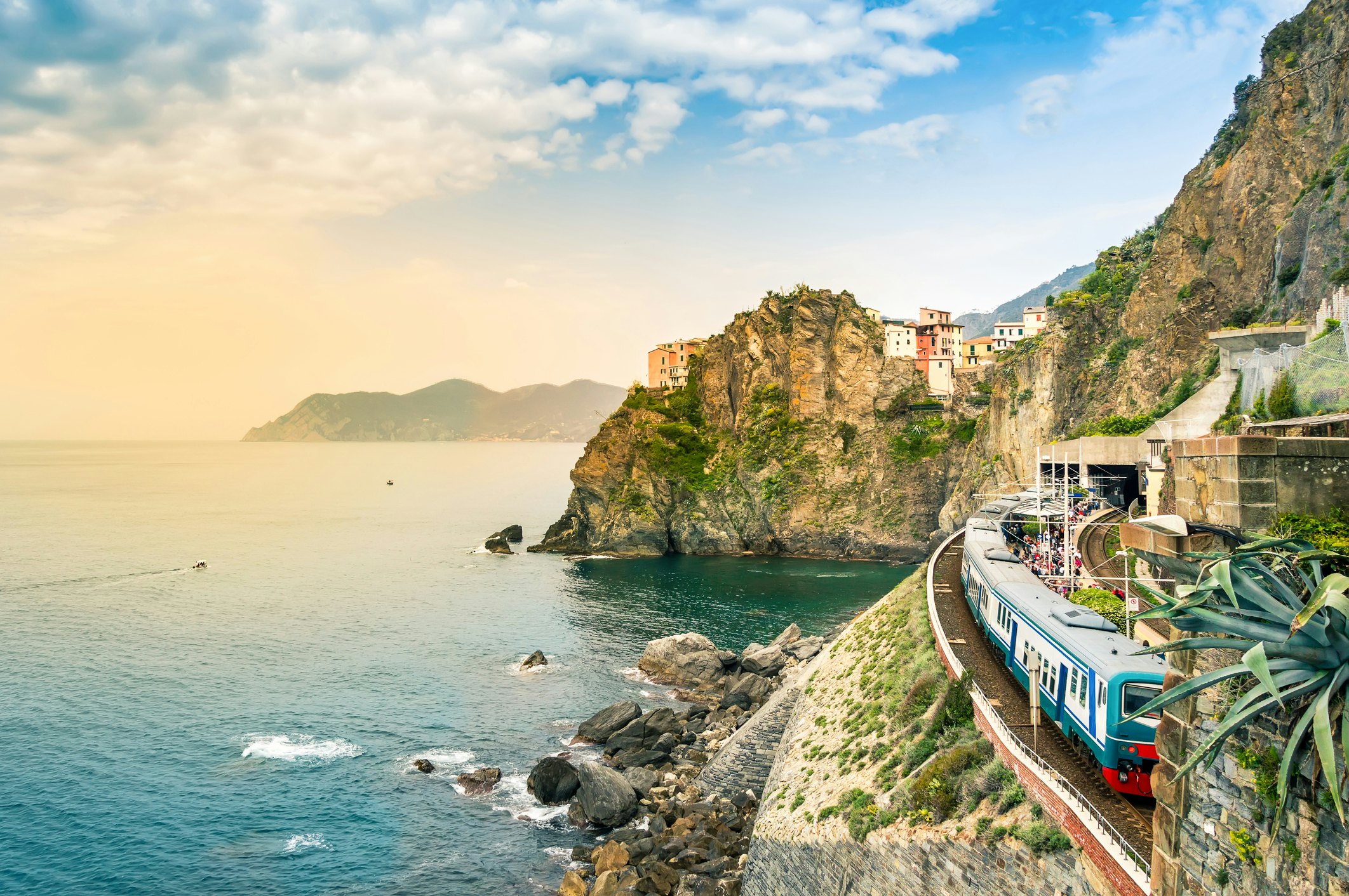 A train at a seaside station in small village with colorful cliffside houses