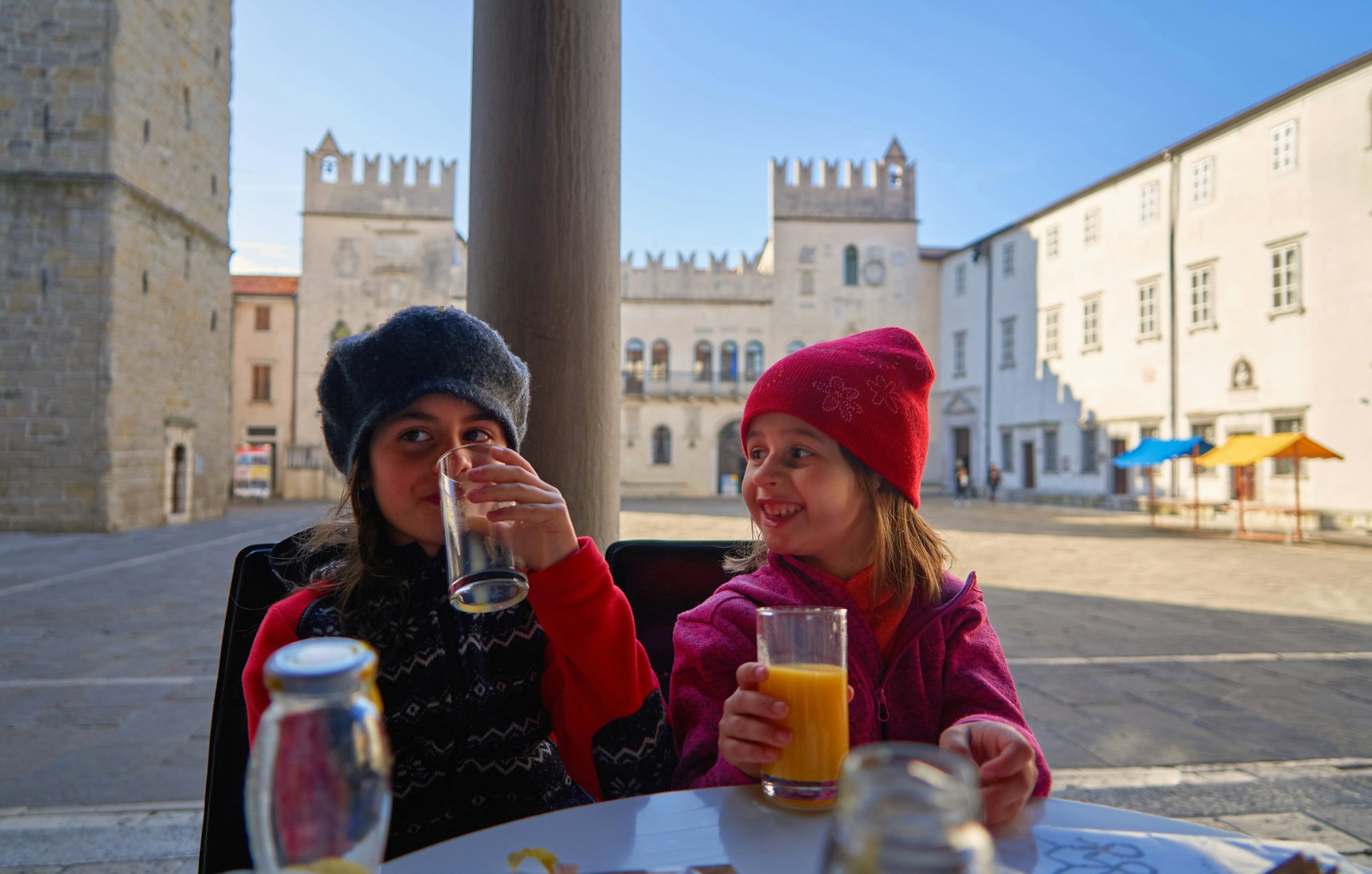 Two children drinking juice at an outside table in the center of Koper, Slovenia