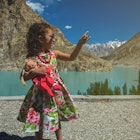 A cute young girl holding a doll in her hands and making hand signs / symbols while on an outdoor expedition on a holiday / vacations while traveling
1196200653