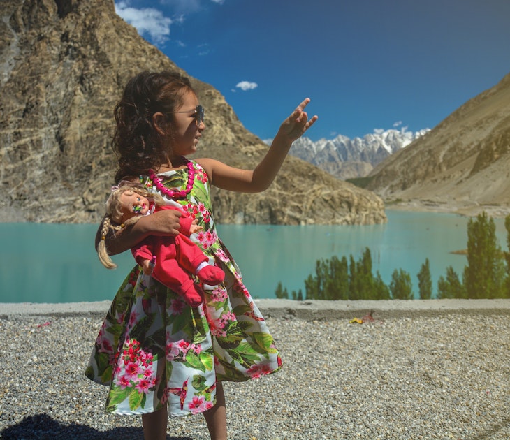 A cute young girl holding a doll in her hands and making hand signs / symbols while on an outdoor expedition on a holiday / vacations while traveling
1196200653