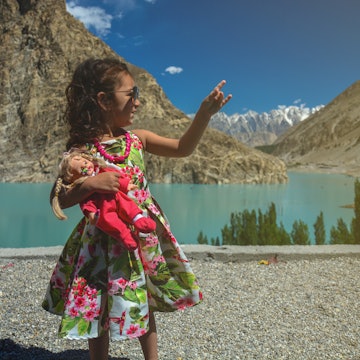 A cute young girl holding a doll in her hands and making hand signs / symbols while on an outdoor expedition on a holiday / vacations while traveling
1196200653
