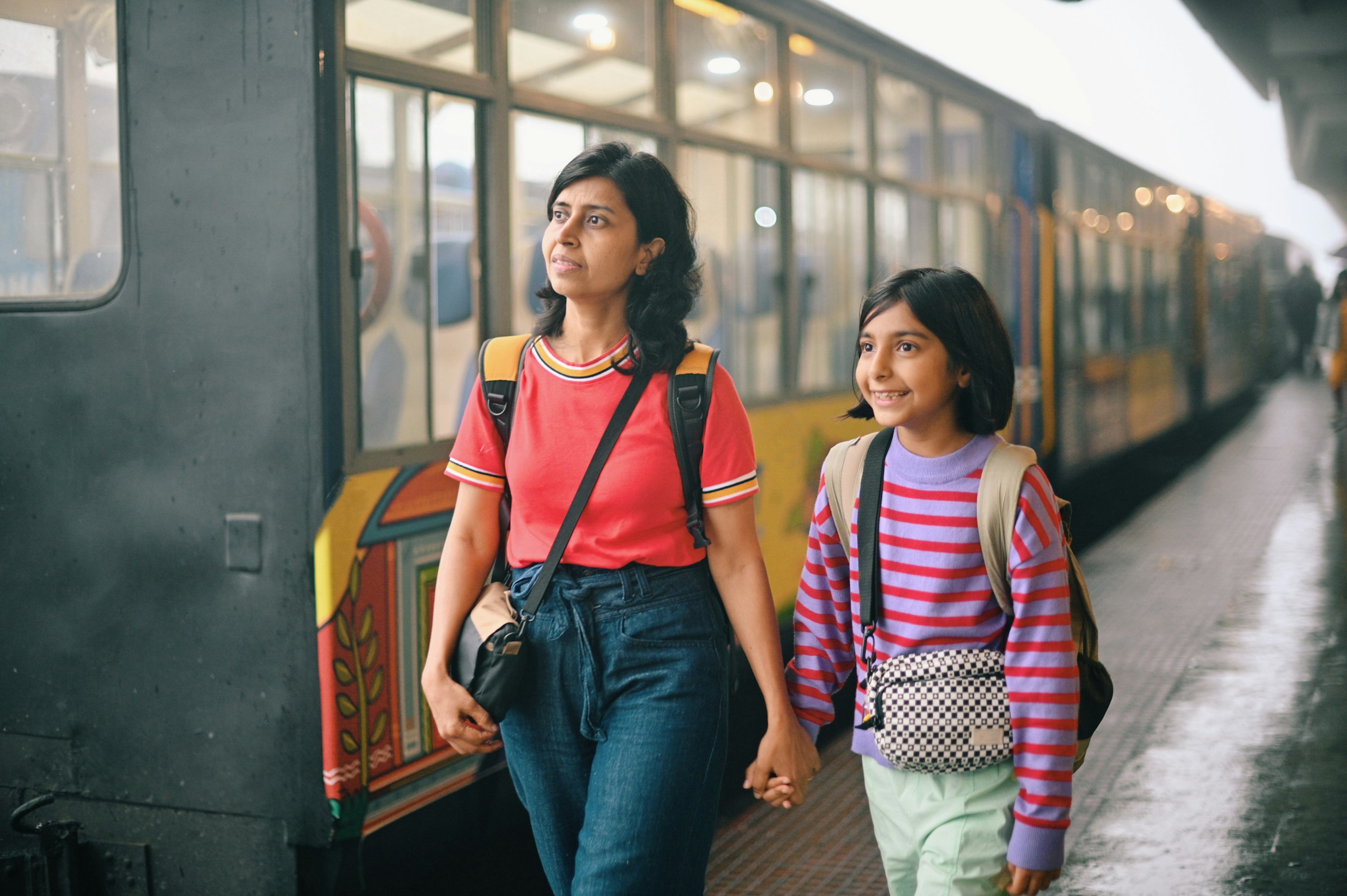 A mother and daughter walking along a train station platform in India