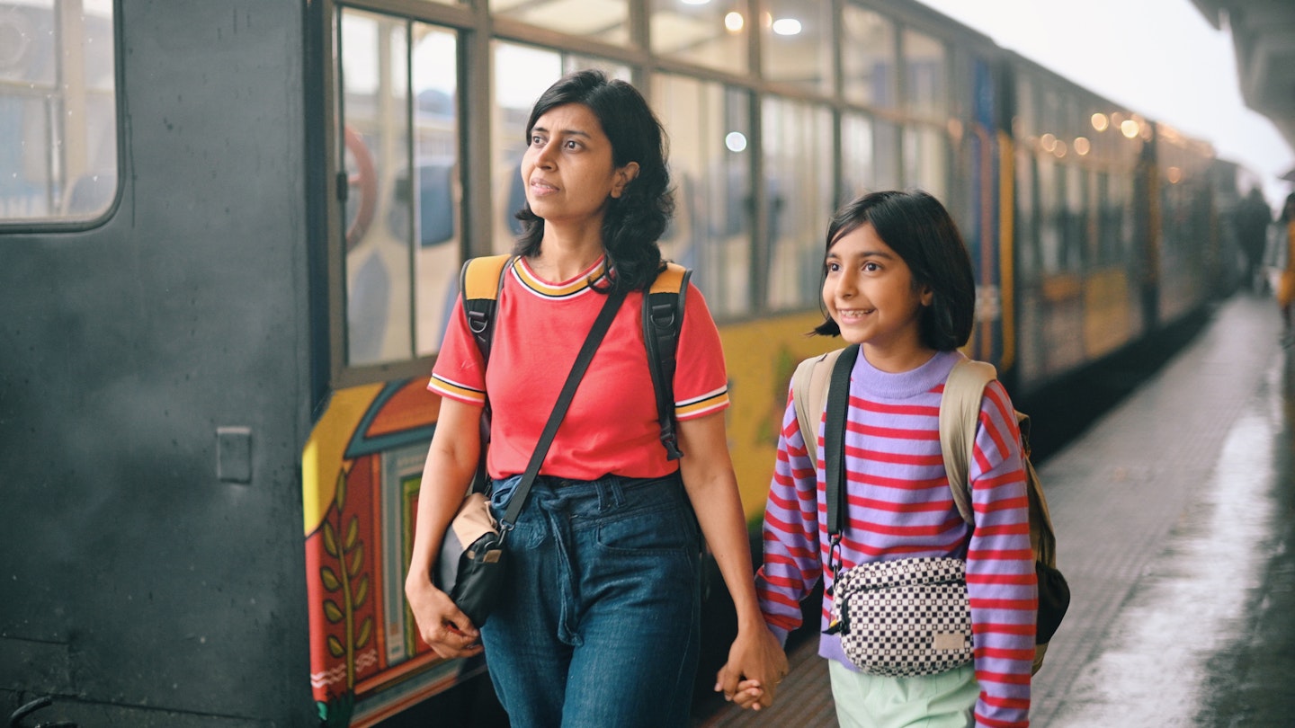 A mother and daughter walking along a train station platform in India