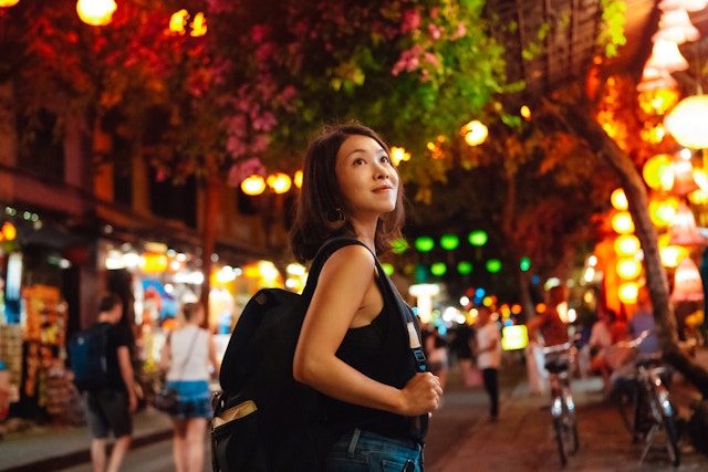 年轻的女性旅行者在春节期间在越南夜间探索当地市场。独奏旅行者。像当地人一样旅行。1450014803年轻的亚洲妇女，背包穿过越南的夜市