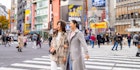 Two women walking across the Shibuya crossing together in Tokyo