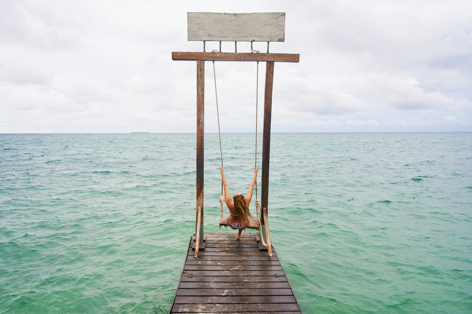 Woman on a swing over the sea in Islas Del Rosario, Colombia