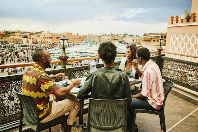 在屋顶餐厅分享食物和饮料的中等镜头，俯瞰Jamaa El Fna Square在马拉克克度假期间1466439690异国旅行