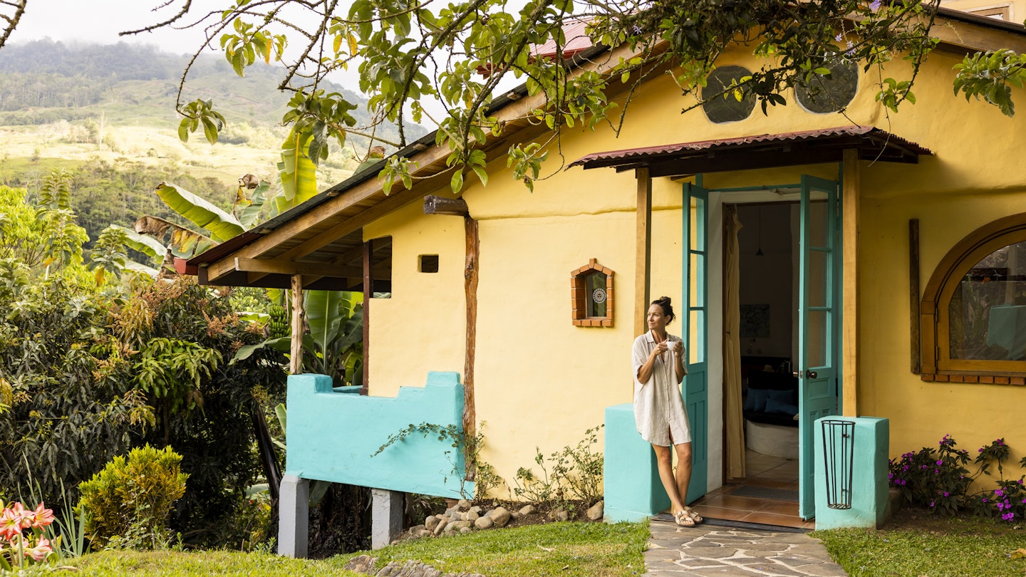 A woman enjoying a cup of coffee outside a cottage in Costa Rica.