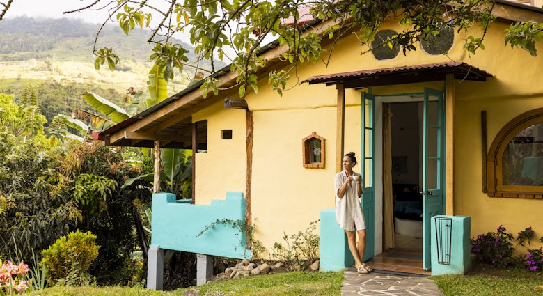 A woman enjoying a cup of coffee outside a cottage in Costa Rica.