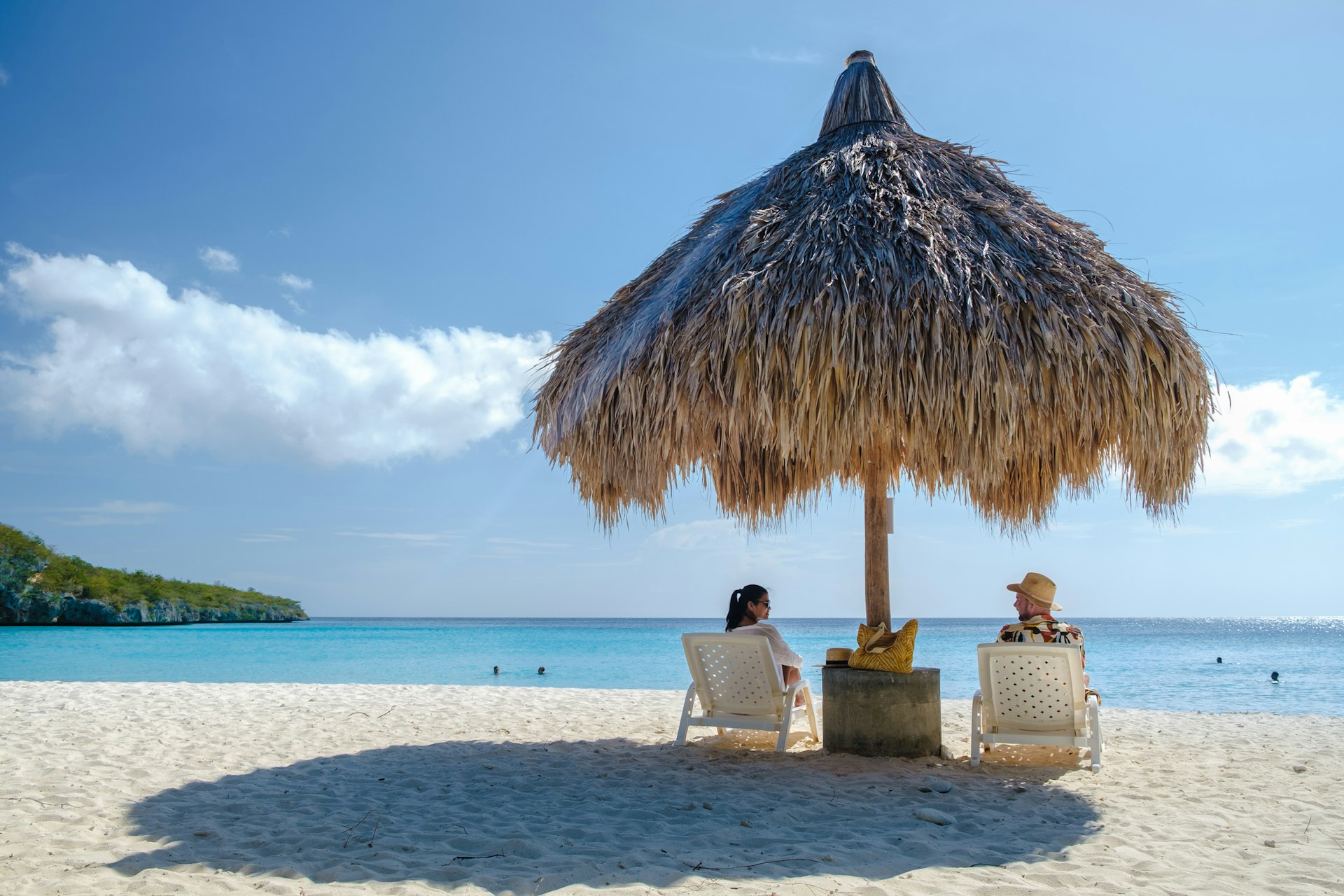 A couple sitting under a parasol on Cas Abao Beach in Curaçao