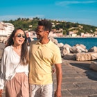 A man and woman walking along the waterfront in a coastal town in Slovenia