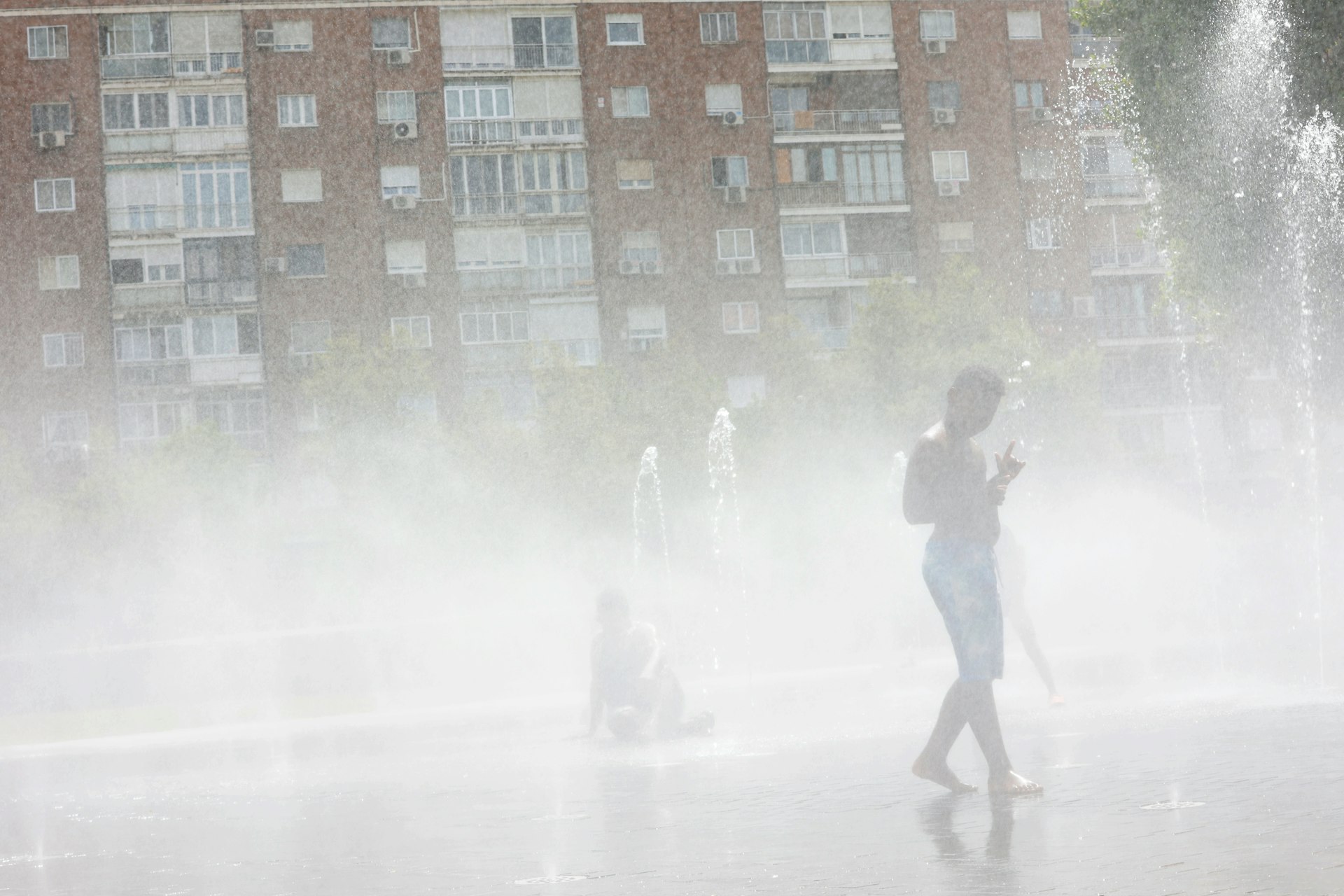 A boy cools off in a fountain on a hot summer day in Madrid, Spain