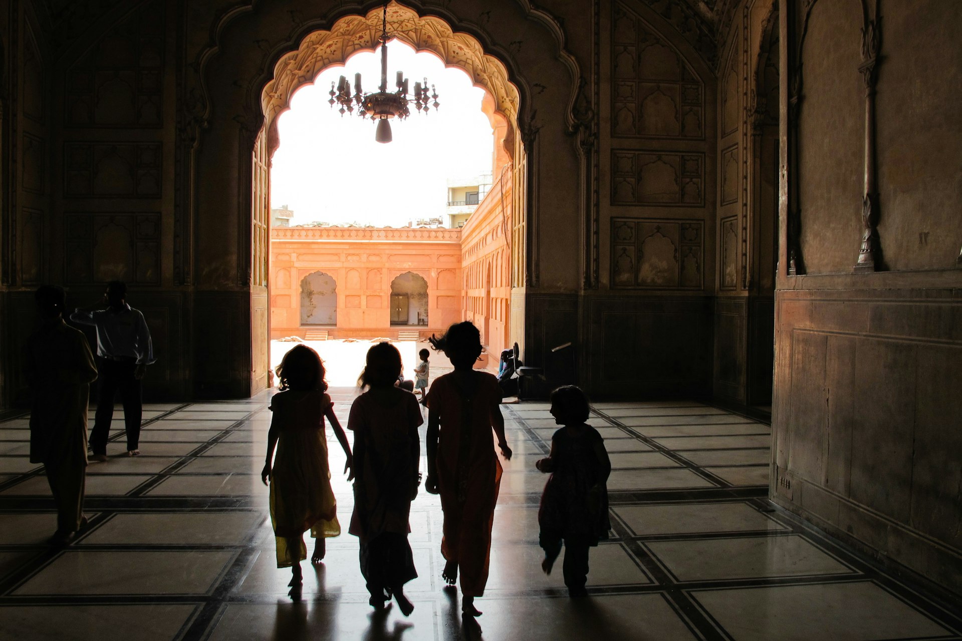 Four children in silhouette as they make their way through a mosque complex