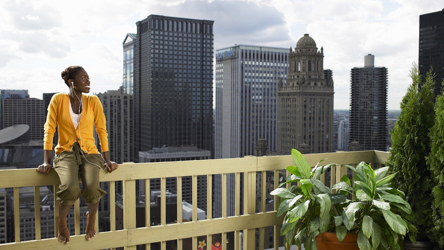 Chicago, Illinois, USA.
200443137-003
A young woman sitting on a rooftop railing with the Chicago skyline in the background