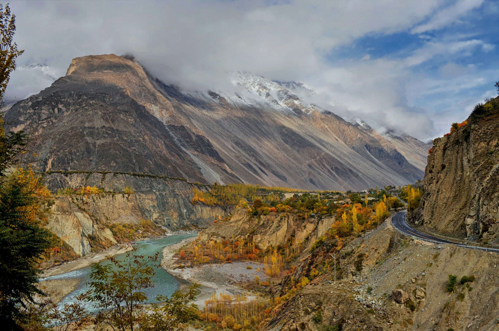 A road runs through a mountain valley alongside a river