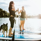 Two young adult friends enjoys a peaceful moment on the water with paddle boards and a faithful pet dog.  The sun illuminates the scene, casting a golden glow. Shot in Austin, Texas, USA.
624744608
Beautiful, City Break, Paddleboard, Pets, Young Women, Women, Two People, Beauty In Nature, Relaxation Exercise, Youth Culture, Dog, 20-29 Years, Young Adult, Exercising, Fun, Healthy Lifestyle, Relaxation, Friendship, Nature, Lifestyles, Outdoors, Recreational Pursuit, People, Austin - Texas, Texas, Lake, River, Paddleboarding
Two women and their dog paddleboarding on a lake in Austin, Texas