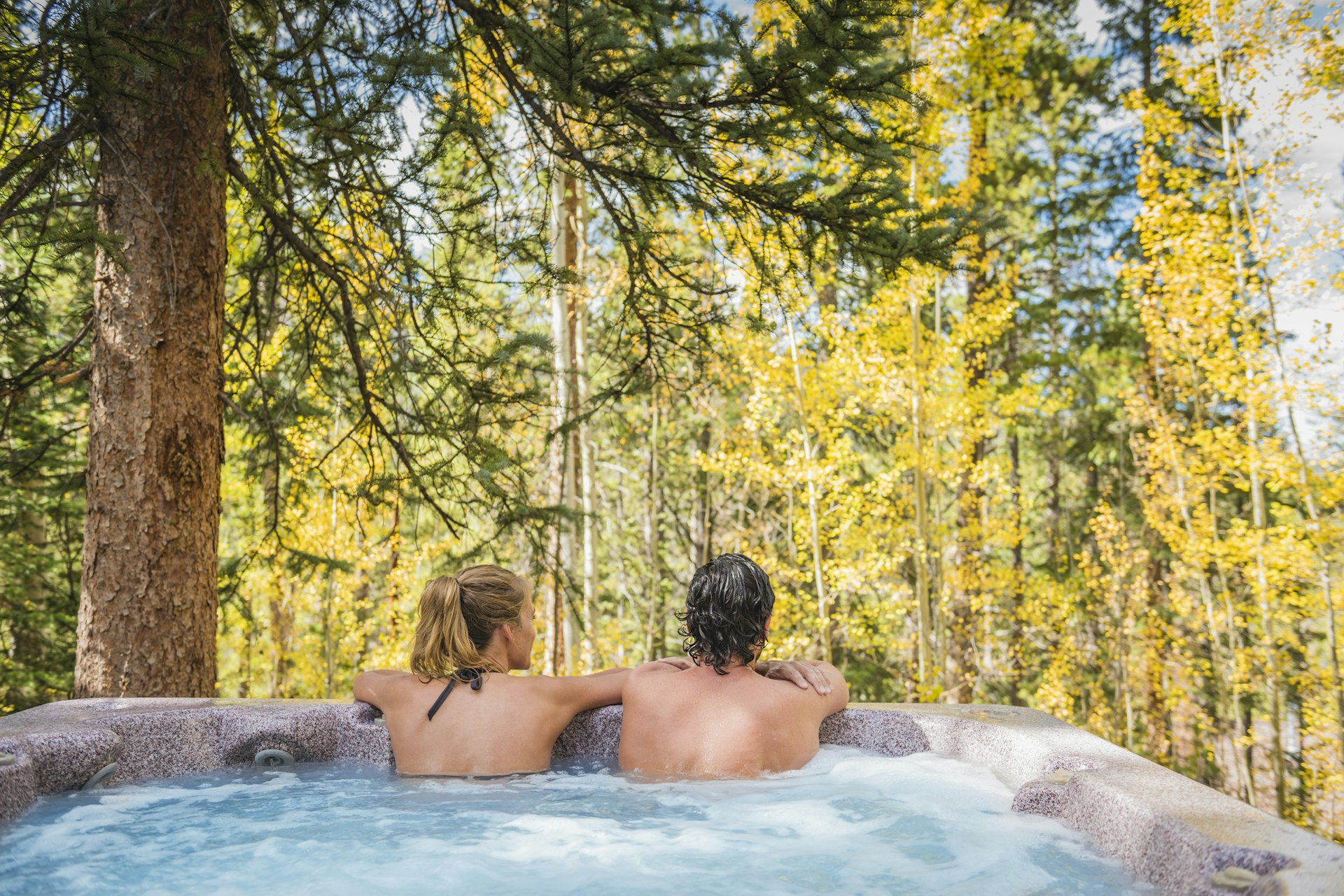 A woman and man in a hot tub looking at the fall foliage in Colorado