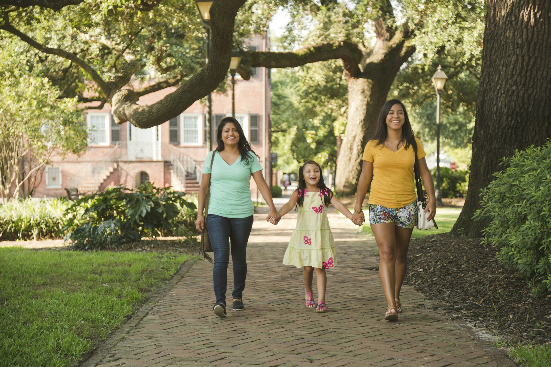 Two women walking through Savannah with their daughter between them, all holding hands