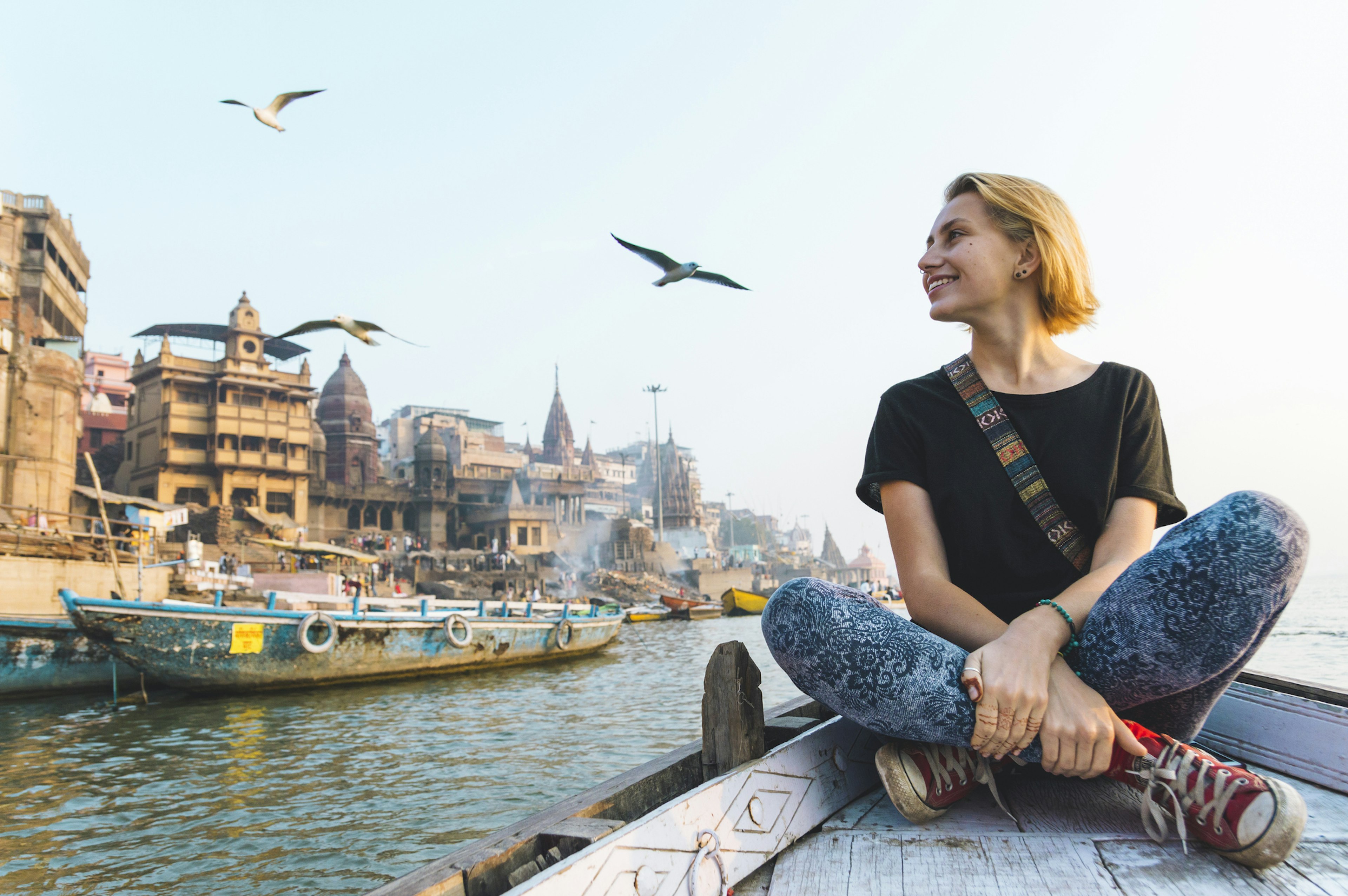 A woman on a boat ride smiles as she looks at the activity on the shoreline