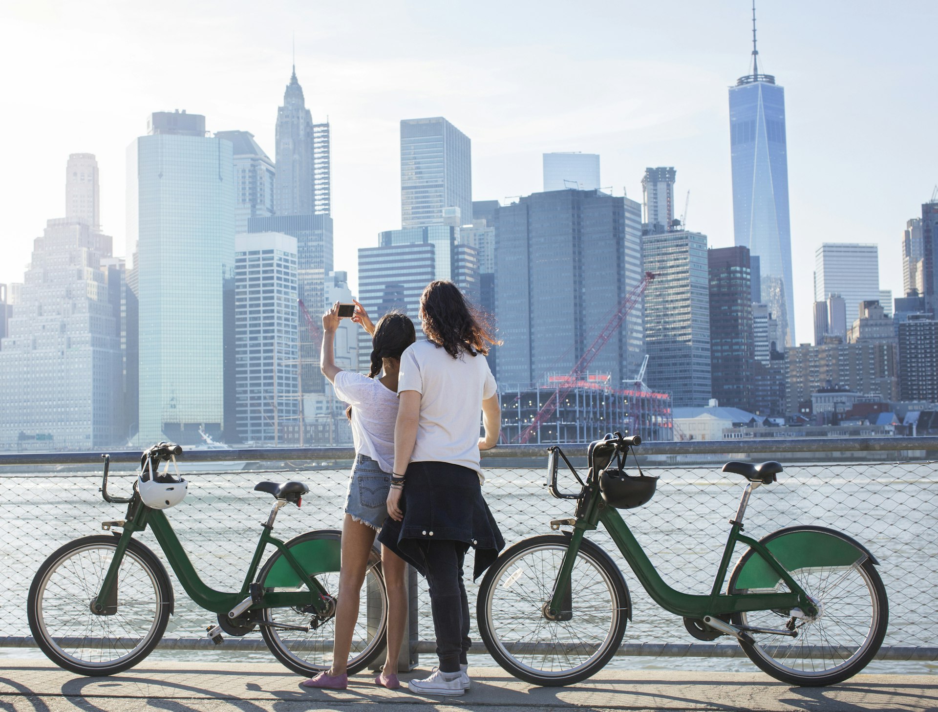A couple with bikes pause to take a photo of the NYC skyline