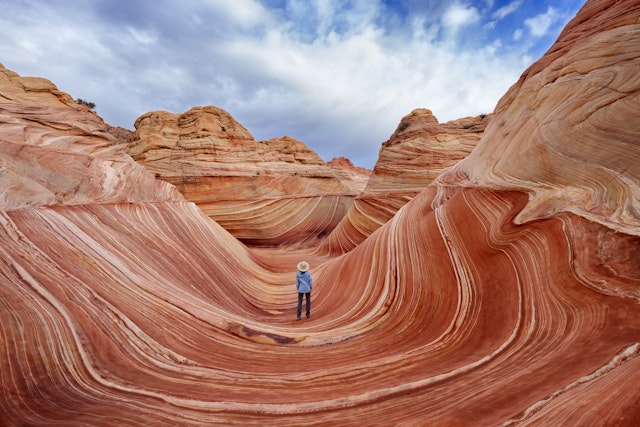 A woman stands among rock formations that appear to curve around her