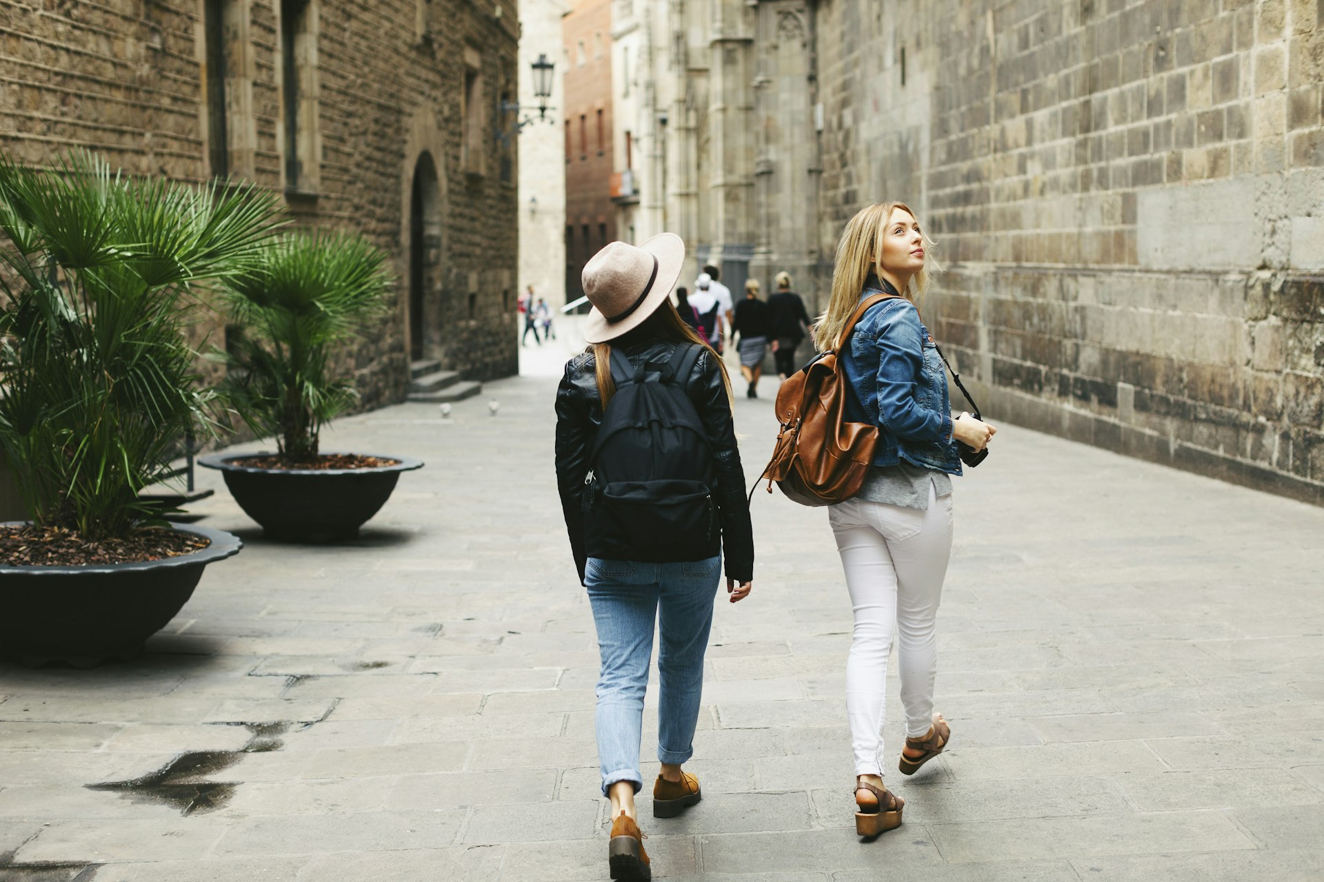 Two women walking along a street in Barcelona as one looks over her shoulder
