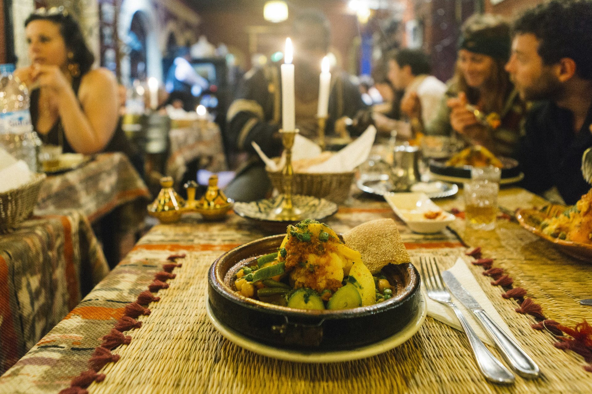 A traditional Moroccan dish on a table in a restaurant packed with diners 