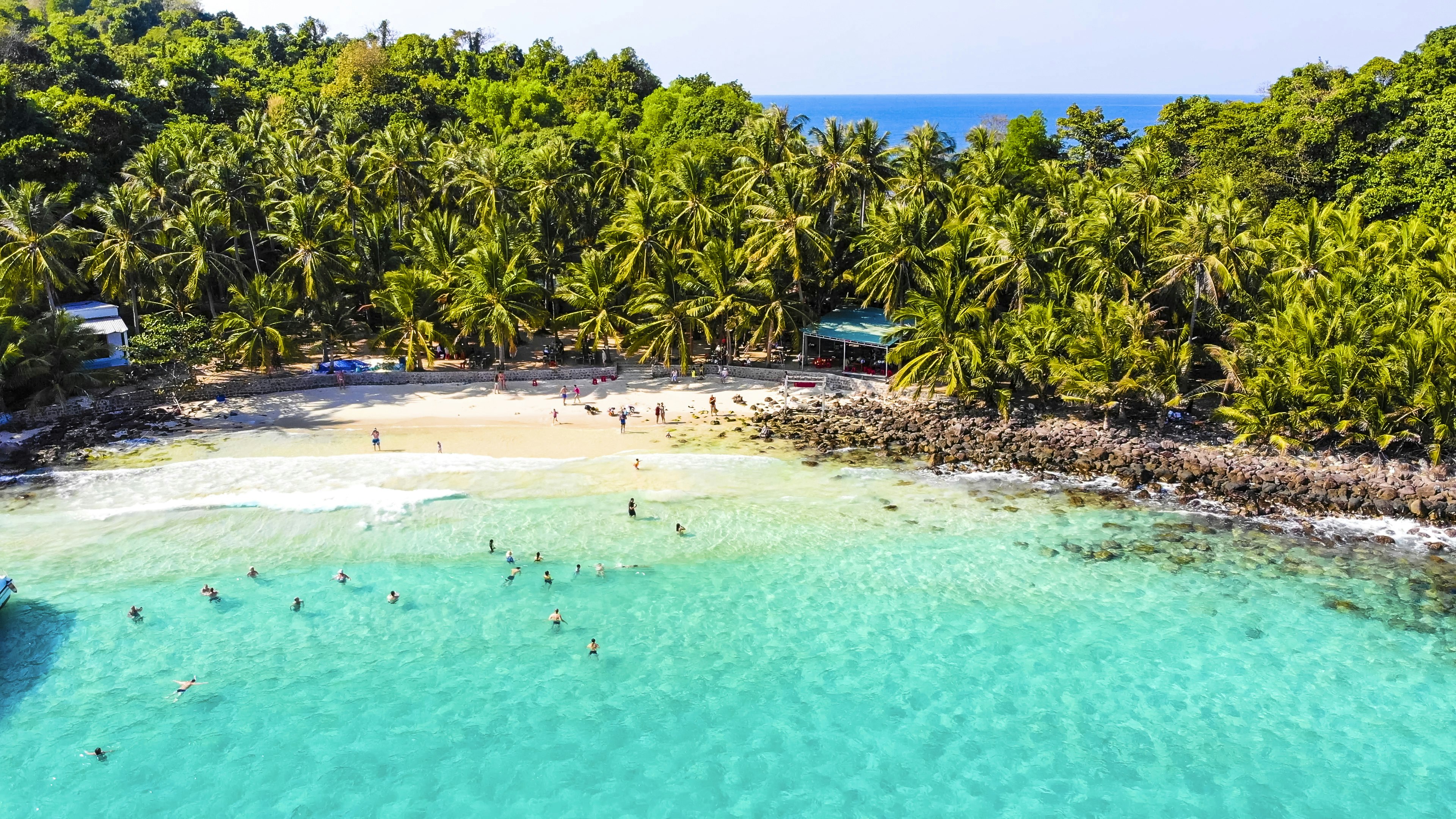 People splash around in the turquoise water of a beautiful island