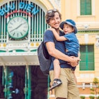 Father and son on background Saigon Central Post Office on blue sky background in Ho Chi Minh, Vietnam. The inscription on the Vietnamese "post office"; Shutterstock ID 1036242475; your: Claire Naylor; gl: 65050; netsuite: Online ed; full: HCMC free update