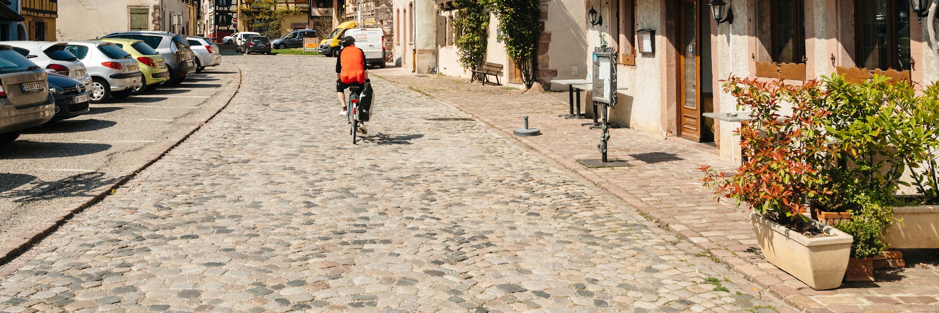 Cyclist on the central cobblestone pavement road of Bergheim, France.