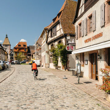 Cyclist on the central cobblestone pavement road of Bergheim, France.