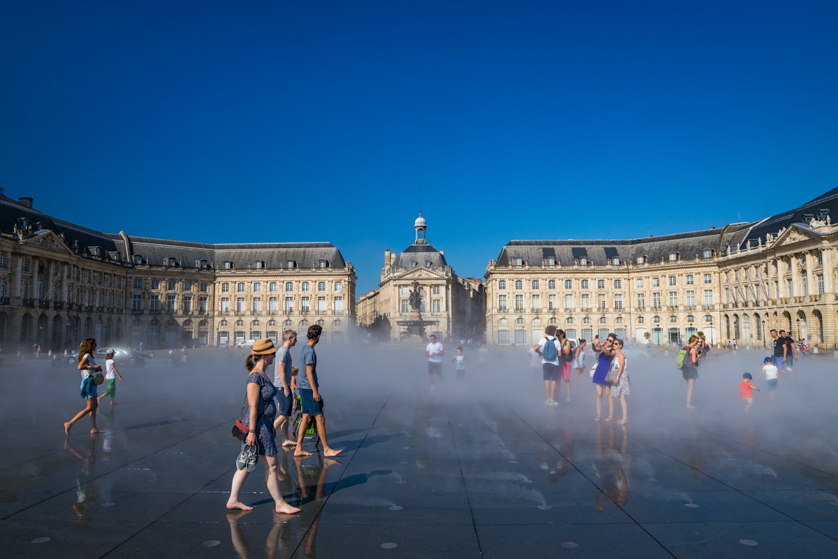 Visitors having fun on the Mirroir d'eau (Water Mirror) of the Place de la Bourse in Bordeaux, France on a hot summer day during a heat wave.