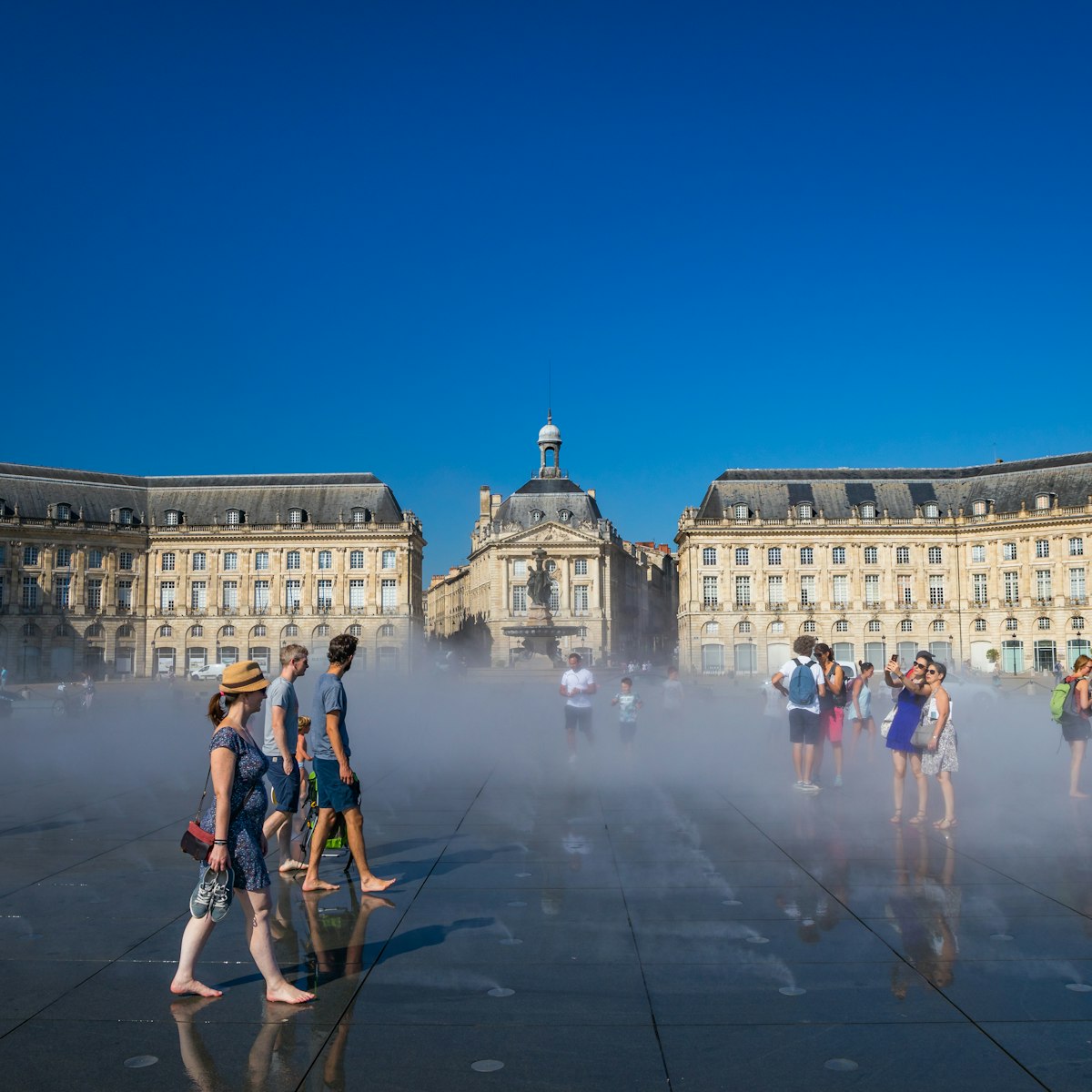 Visitors having fun on the Mirroir d'eau (Water Mirror) of the Place de la Bourse in Bordeaux, France on a hot summer day during a heat wave.