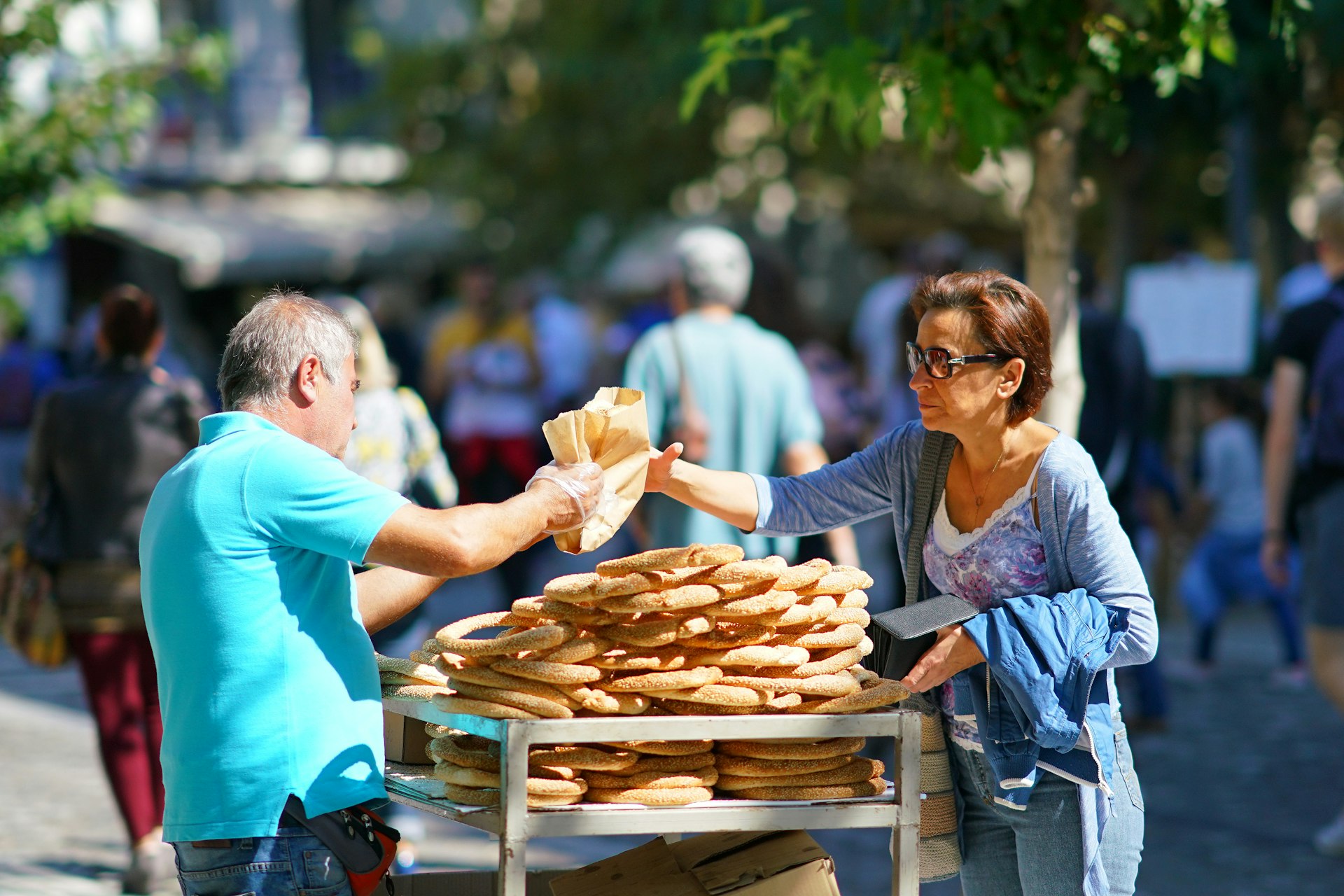 A woman buys bread rings from a street vendor in Athens