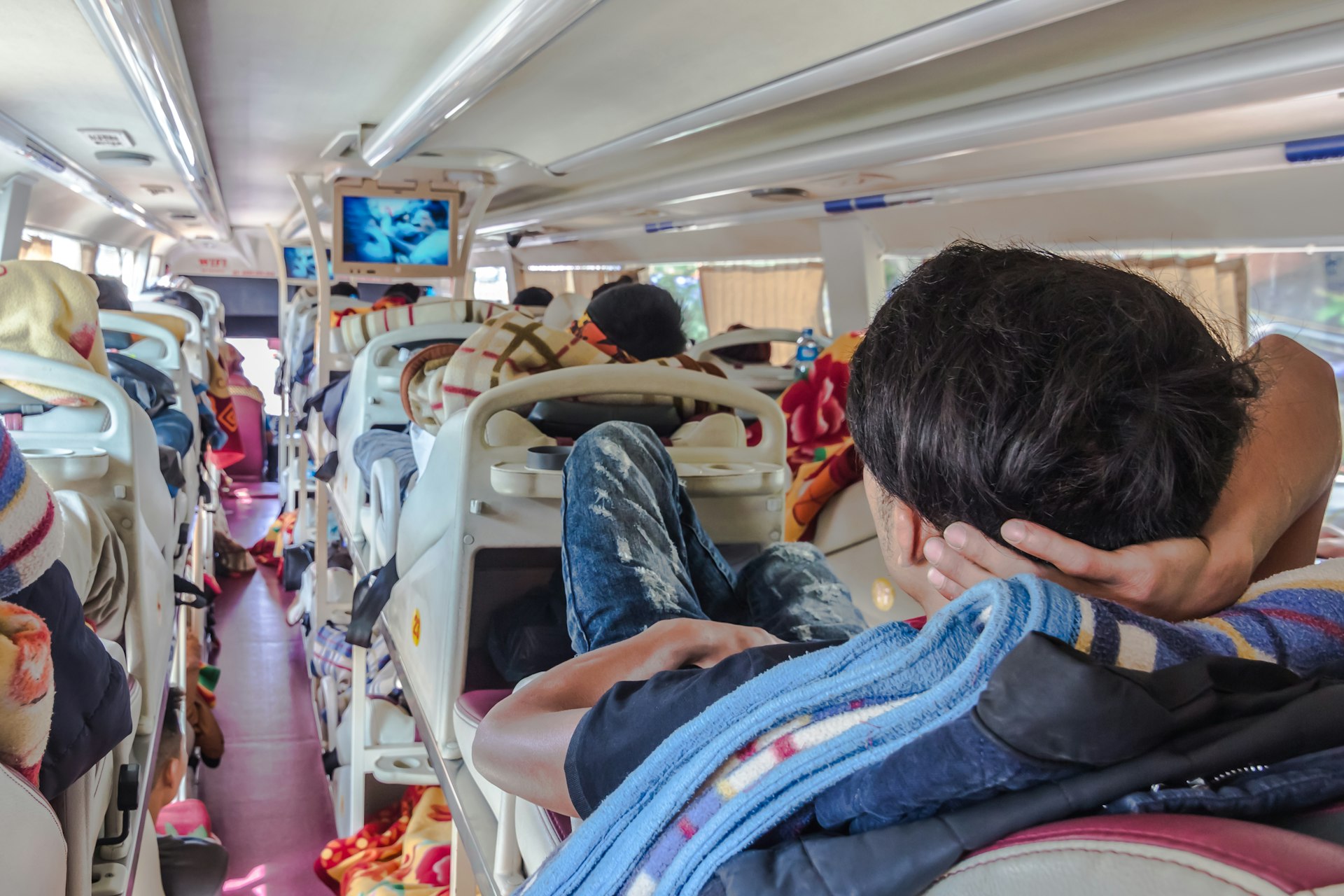 A man watching TV on a long distance sleeper bus in Asia
