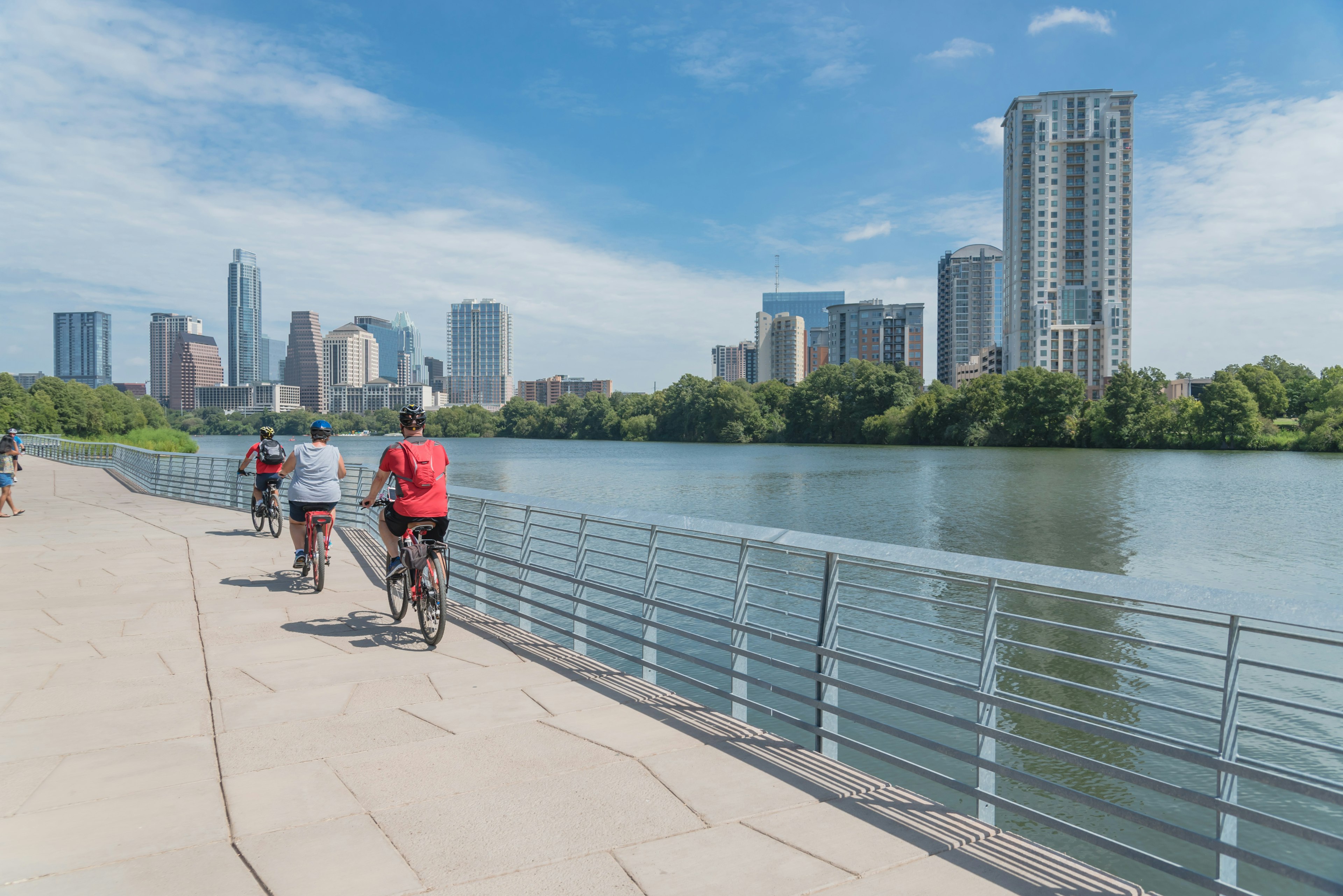 People biking along a waterfront boardwalk on a summer's day