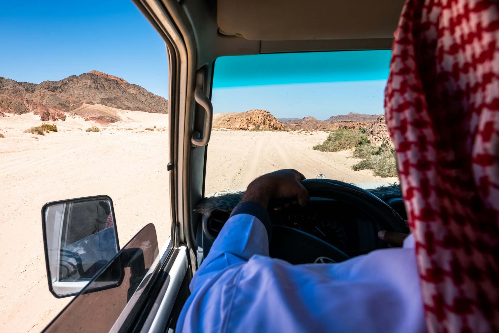 A man drives a car through the desert