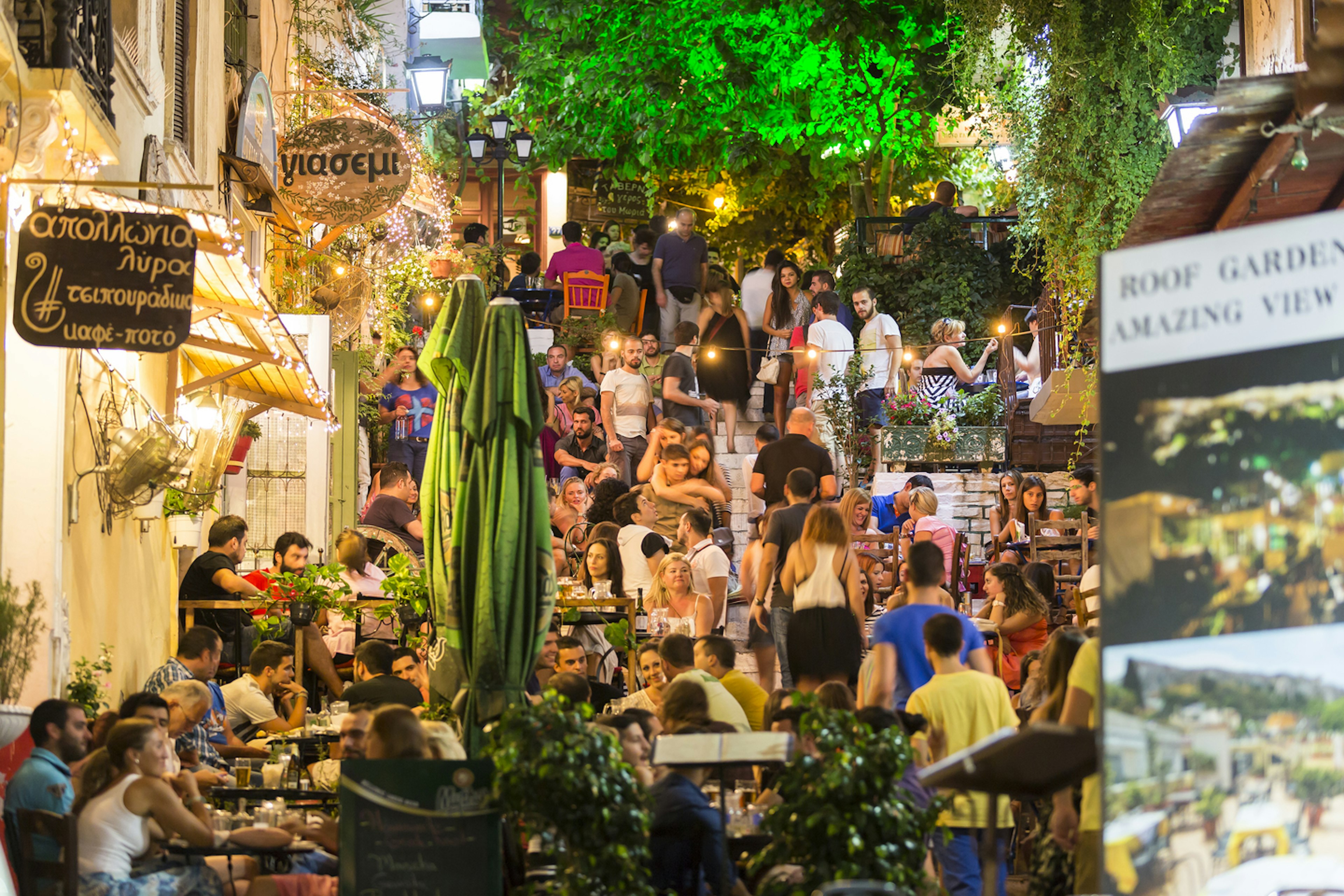 Crowds of people fill tables that stretch uphill outside restaurants