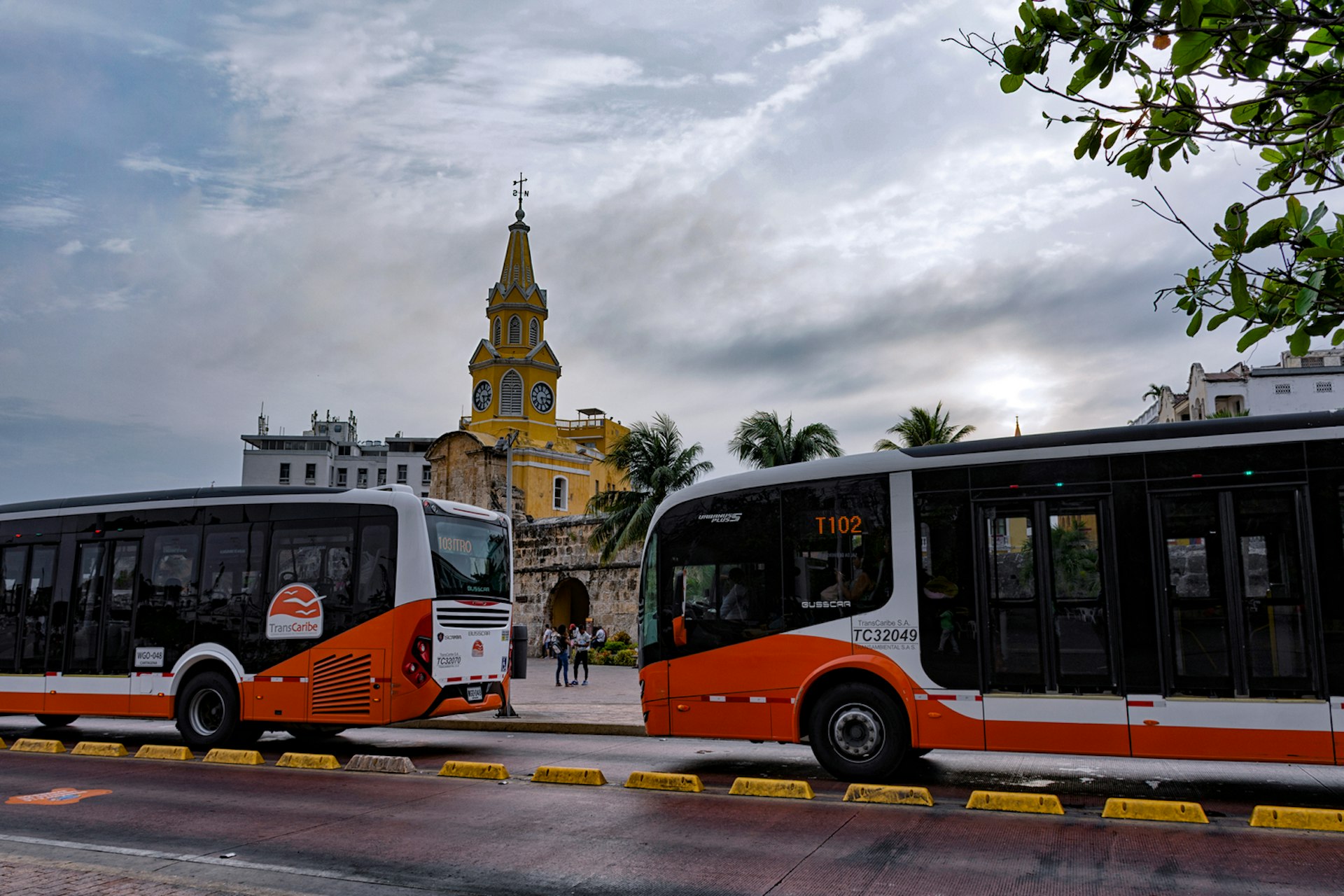 Two orange and white buses parked outside the Old Town