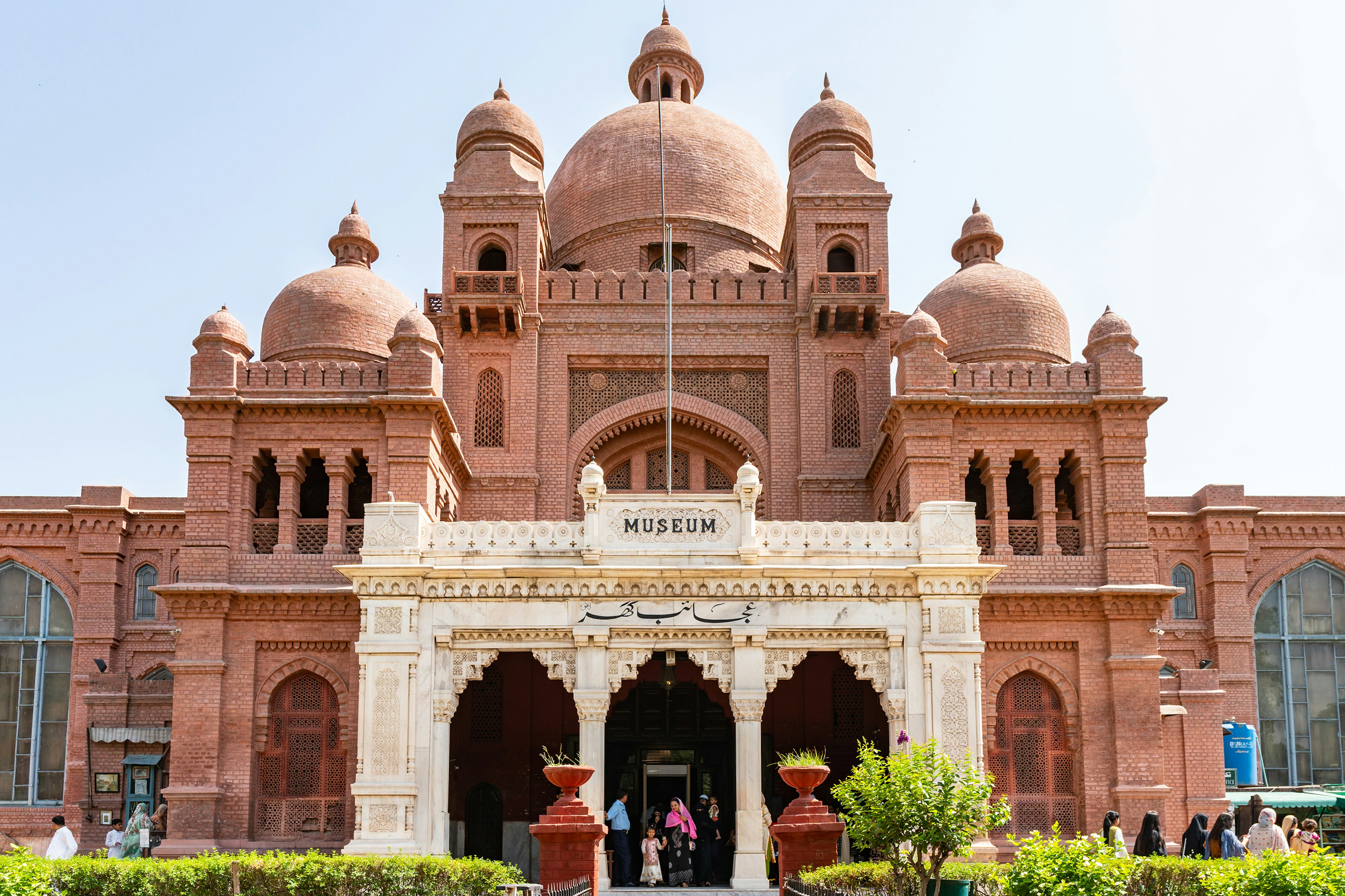 A large domed red building with the word MUSEUM above the door where people are entering