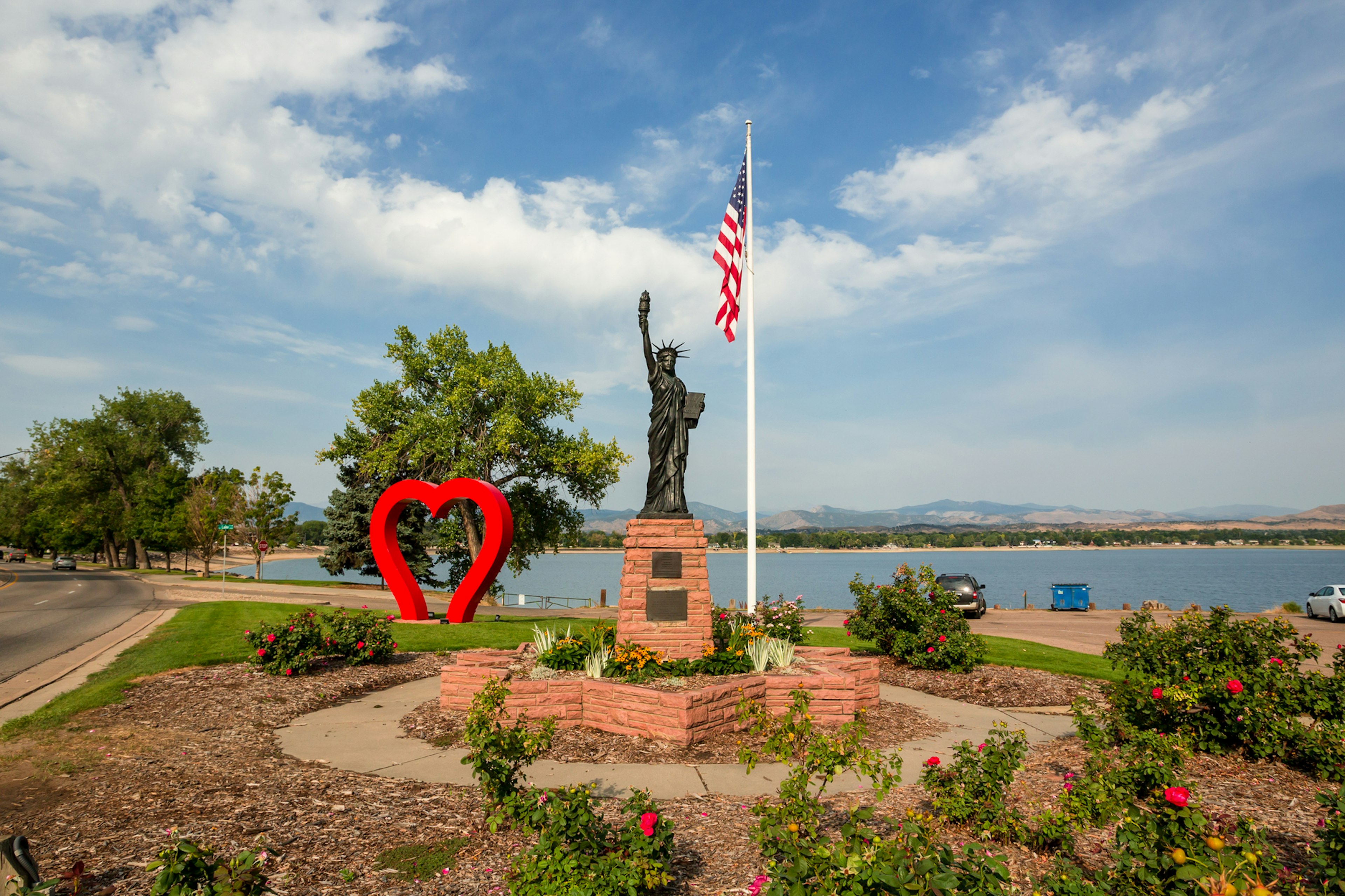 A red heart sculpture next to a miniature version of the Statue of Liberty